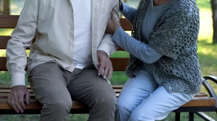 Mujer apoyando a un viejo amigo enfermo, sentada en un parque del hospital, enfermedad de Parkinson