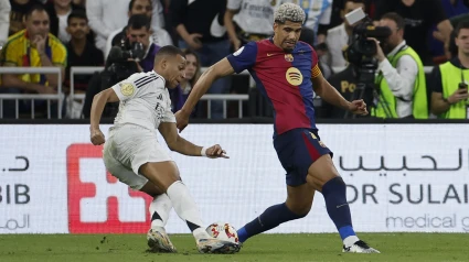 El defensa uruguayo del Barcelona Ronald Araujo (d) pelea un balón con el delantero francés del Real Madrid Kylian Mbappé durante el partido de la final de la Supercopa de España