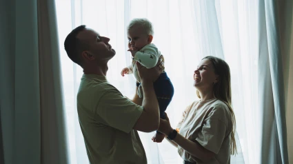 Una pareja de familia feliz con un pequeño hijo en brazos. Mamá, papá y el bebé se abrazan.