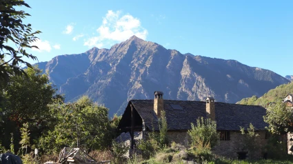 Una casa de piedra rodeada de naturaleza con vistas a los Pirineos en un día soleado, en el encantador pueblo español de Taull.