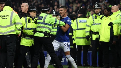 Carlos Alcaraz, jugador del Everton es agarrado por una policía inglesa para evitar que se una a la pelea.