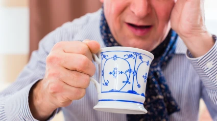 Un hombre mayor bebe de una taza