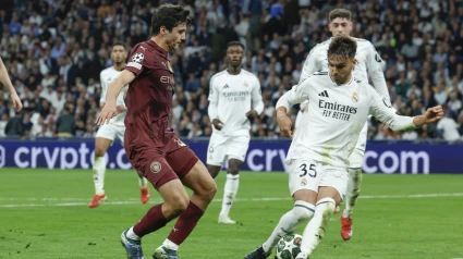 El defensa uzbeko del Manchester City Abdukodir Khusanov (i) lucha con Raúl Asencio, del Real Madrid, durante el partido de vuelta de la eliminatoria previa a los octavos de final de la Liga de Campeones que Real Madrid y Manchester City disputan hoy miércoles en el estadio Santiago Bernabéu