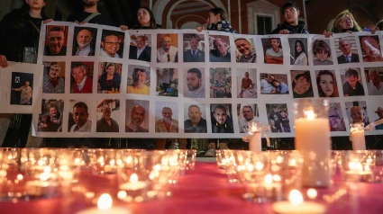 Varias personas sostienen un cartel con imágenes de algunos fallecidos, durante una conmemoración por las víctimas de la DANA en Valencia