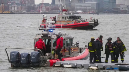 Los buzos del Departamento de Bomberos de Nueva York regresan al muelle 40 en la costa de Nueva York mientras los barcos de rescate buscan el helicóptero turístico que se estrelló sobre el río Hudson