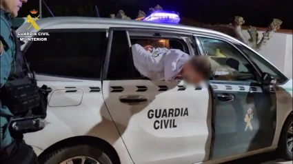 Trata de salir por la ventanilla del coche patrulla de la Guardia Civil