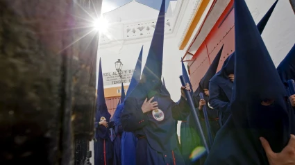 Nazarenos de la Hermandad del Baratillo pasan junto a la Real Maestranza de Sevilla