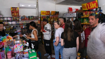 Vecinos de Elche compran en una tienda de ultramarinos durante el apagón eléctrico que se ha producido hoy lunes en la Península Ibérica