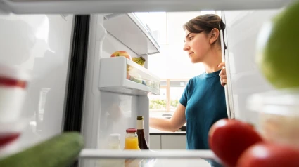 Mujer en el refrigerador abierto en la cocina de casa
