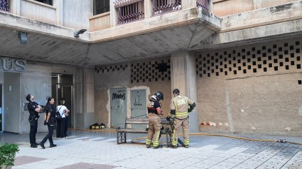 Policías y bomberos ante el portal del edificio en el que se produjo el incendio