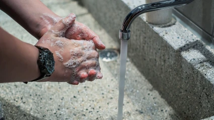 Una persona lavándose las manos con agua y jabón