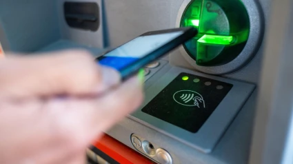Una persona opera con su teléfono inteligente en un cajero automático utilizando la opción inalámbrica o sin contacto