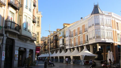 Vista de la Calle Mayor durante la pandemia con puestos de mercado bajo cenadores, peatones y la estatua de la Mujer Palencia