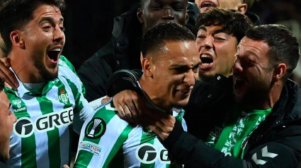 Antony, con gesto emocionado, recibe el abrazo de sus compañeros para celebrar el pase del Betis a la final de la Conference