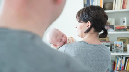 Madre sosteniendo a su hijo llorando mientras el padre está en primer plano