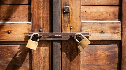 Puerta de madera cerrada con dos candados