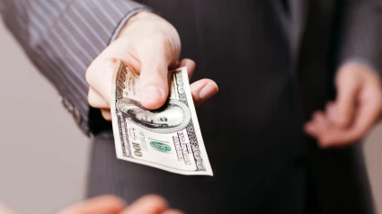Un chico estira un billete de 100 dólares