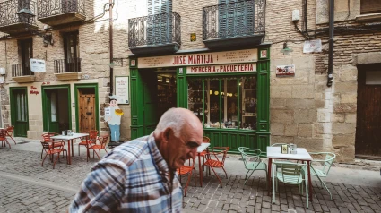 Hombre mayor caminando frente a una tienda tradicional en el casco antiguo de Pamplona, Navarra
