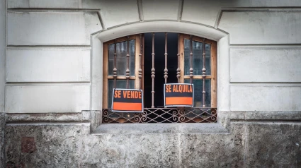 Rótulos de inmobiliaria ('se vende', 'se alquila', en español) en una ventana de Valencia