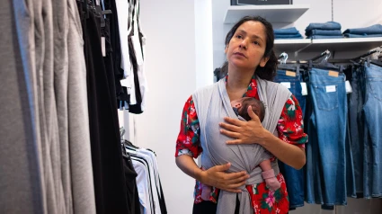 Una madre con un bebé recién nacido en portabebés es vista comprando en una tienda de ropa en el centro de la ciudad, en Passeig de Gràcia.