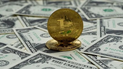 Una moneda de Bitcoin sobre dólares
