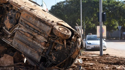 Parte inferior del coche volcada y cubierta de barro a un lado de la calle tras la inundación de la DANA. Valenciano
