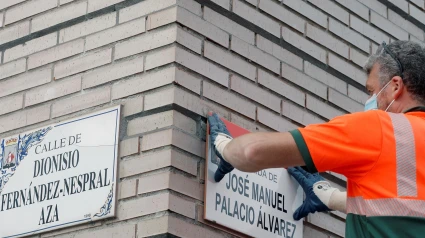 Un operario cambia la placa de la avenida de Juan Carlos I por la de José Manuel Palacio, en Gijón