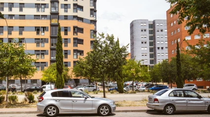 Una calle de la ciudad en un soleado día de verano. Coches aparcados al borde de la carretera. Edificios de varias plantas en un tranquilo y moderno barrio residencial.
