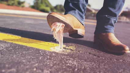 Un hombre pisa un chicle pegado sobre el asfalto