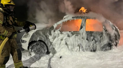 Un bombero sofocando las llamas de uno de los vehículos