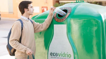 Un joven deposita una botella en el contenedor del vidrio