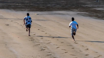 Dos hombres corriendo por la playa