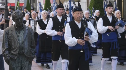 Grupo de gaiteros pasan ante la estatua de Woody Allen durante la fiesta del Martes de Campo