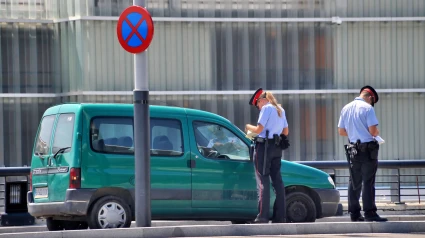 Dos agentes del tráfico españoles multando a una furgoneta por aparcar en un lugar prohibido