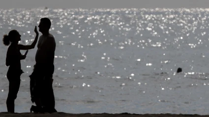Una pareja se aplica crema solar en la playa de la Malvarrosa, en Valencia