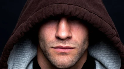 BF5GHX BF5GHX An evil looking man wearing a hooded top with his eyes hidden against a black background.