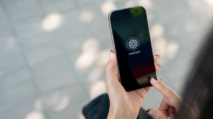Una mujer utilizando la aplicación de ChatGPT en su teléfono móvil mientras está en la calle