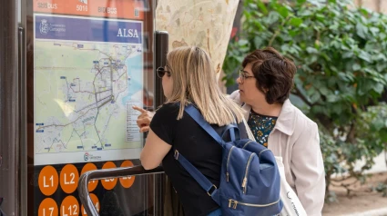 Dos personas consultan la información de las líneas de autobús