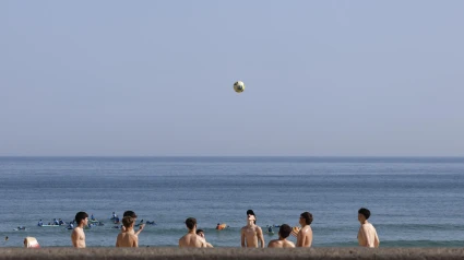 Unos jóvenes juegan con un balón en la playa de la Zurriola de San Sebastián.