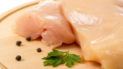 E7HYMG E7HYMG Raw chicken meat on cutting board with pepper and parsley