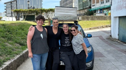 Inma Nespereira, acompañada de voluntarias del equipo, llevando colchones sobre el vehículo