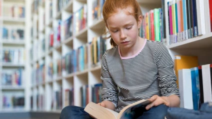 Niña leyendo en una biblioteca