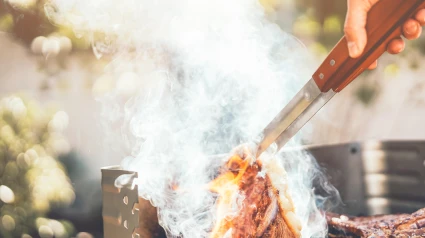 Un hombre chef asa un filete de res en una cena de barbacoa al aire libre
