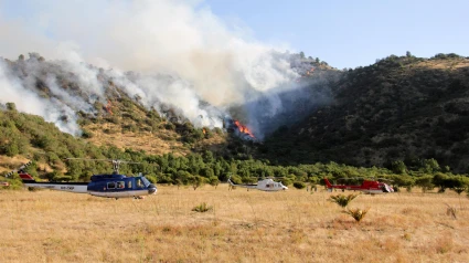 Incendi forestal amb helicòpters en primer pla.