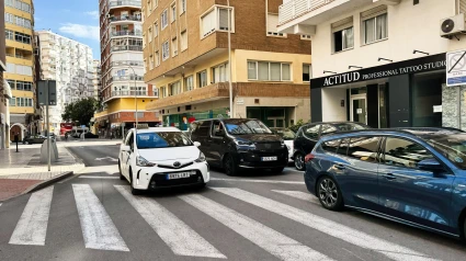 Calle de la ciudad con coches aparcados, edificios y un estudio de tatuajes en Málaga