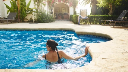 Mujer nadando en la piscina de un apartamento vacacional