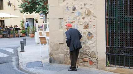 Anciano con gorra roja caminando por la calle, Cáceres
