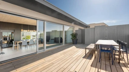 Elegant and modern rooftop patio deck with a picknick table and chairs. Floor to ceiling sliding doors open up to a loft apartment