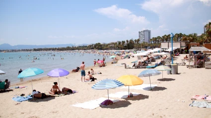 Turistas y bañistas tomando el sol y bañándose en la playa de Salou