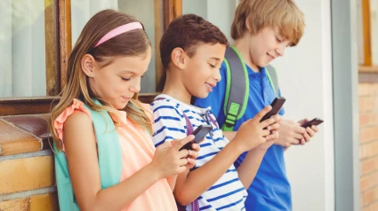 Tres niños utilizan sus móviles en un centro educativo